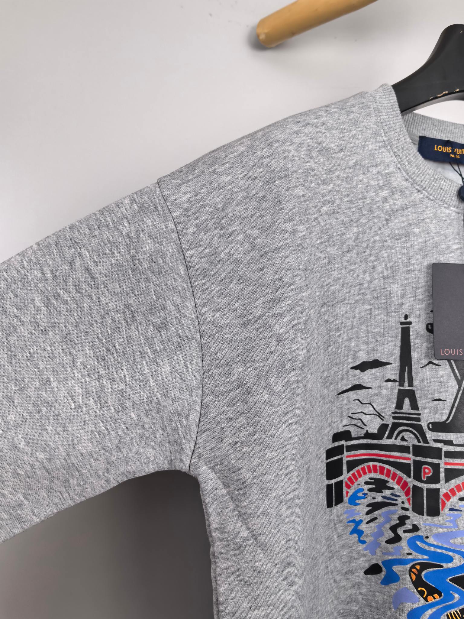 Grey crewneck sweatshirt sleeve detail with part of the graphic print