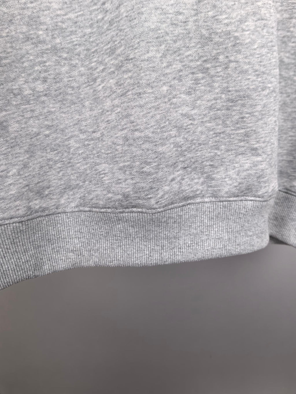 Grey crewneck sweatshirt cuff and lower hem detail