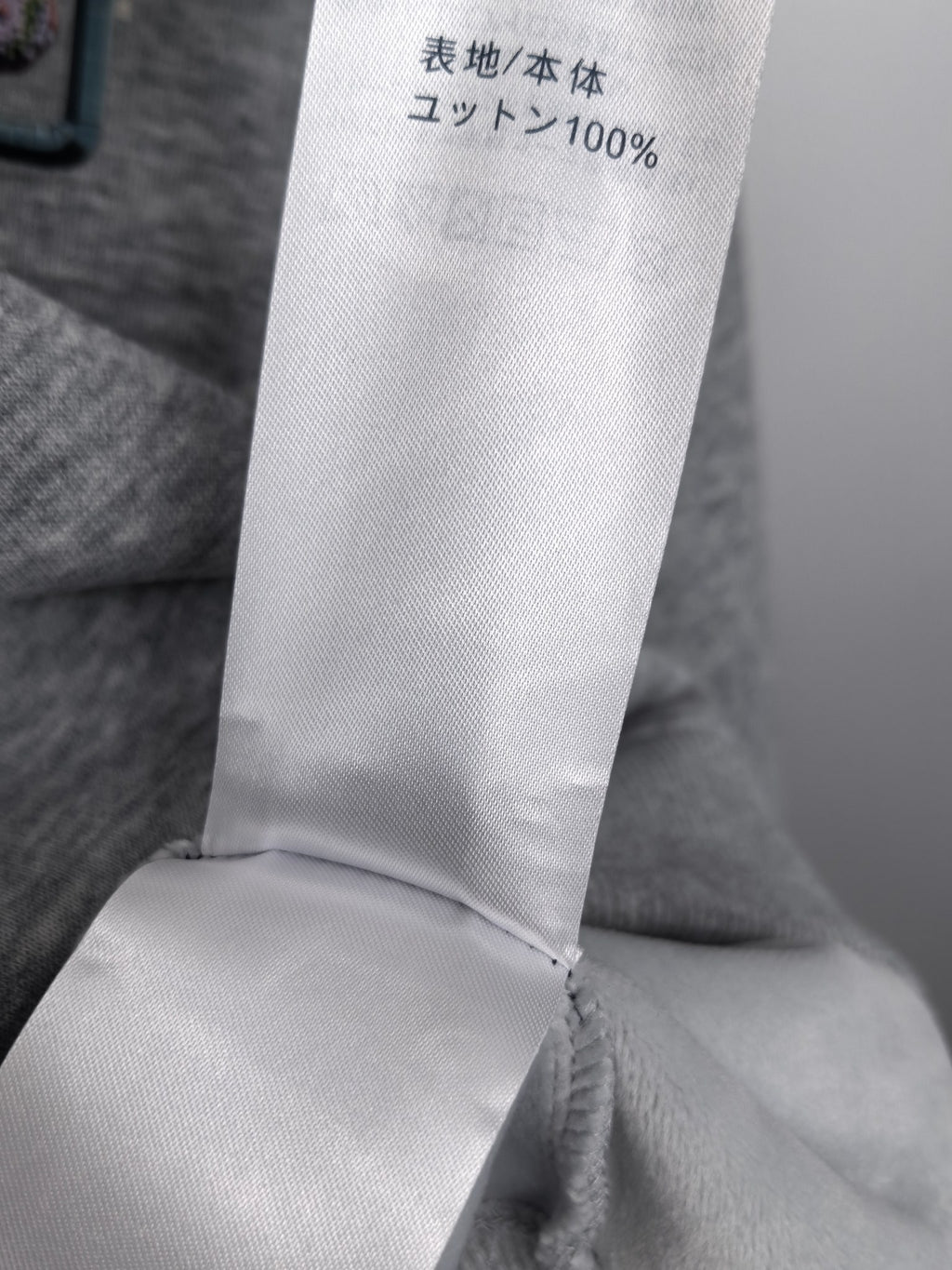 Gray sweatshirt fabric content label showing 100% knit