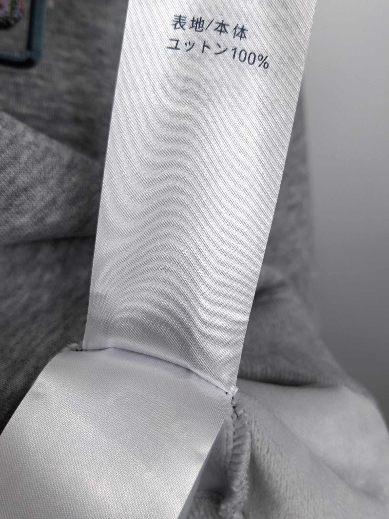 Gray sweatshirt fabric content label showing 100% knit