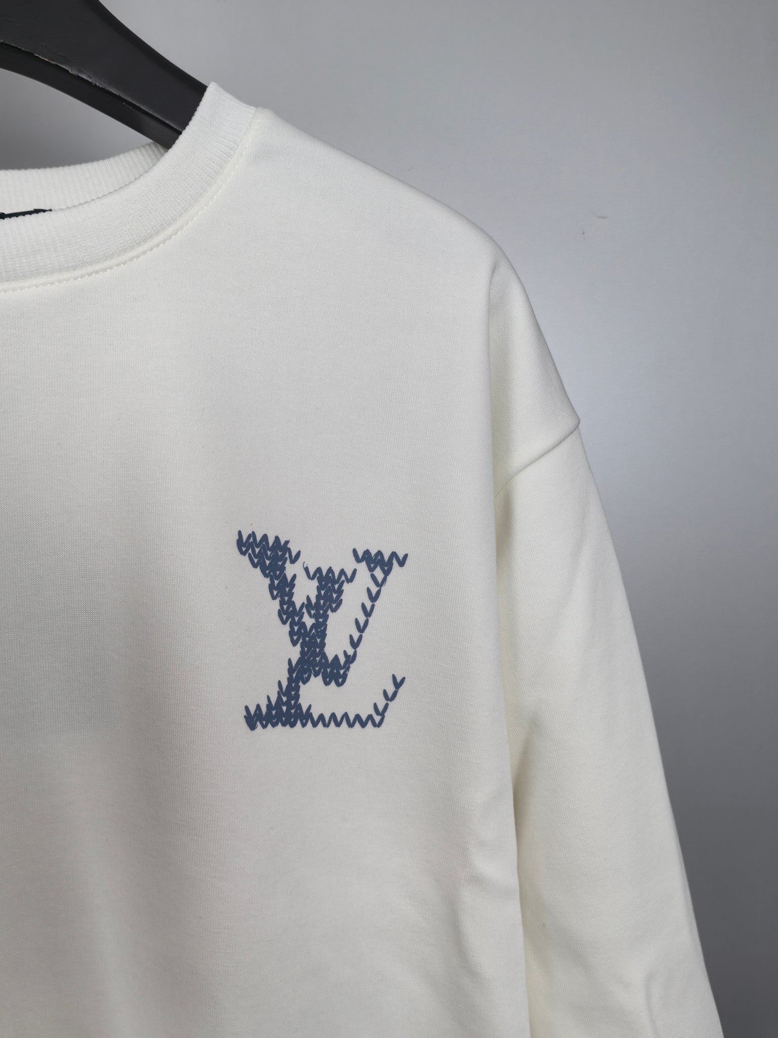 White sweatshirt with blue star-style LV logo on sleeve