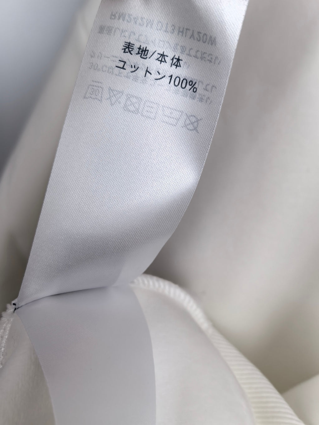 White sweatshirt care label with "100%" and wash symbols