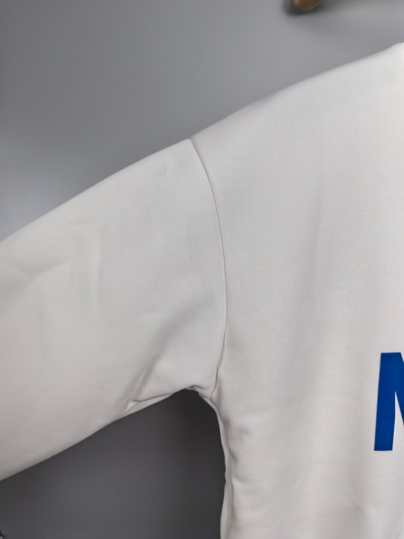 Louis Vuitton white sweatshirt sleeve with partial blue “LE” lettering