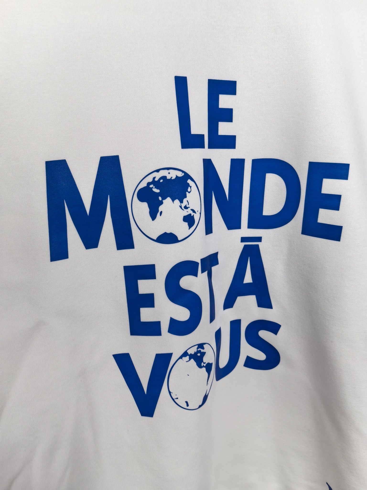Louis Vuitton white sweatshirt with large blue “LE MONDE ESTÀ VOUS” graphic