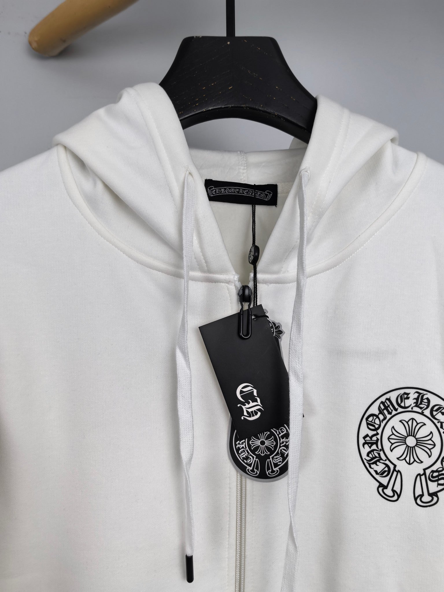 White zip-up hoodie with hood and drawstrings, showing hanging size/brand tag