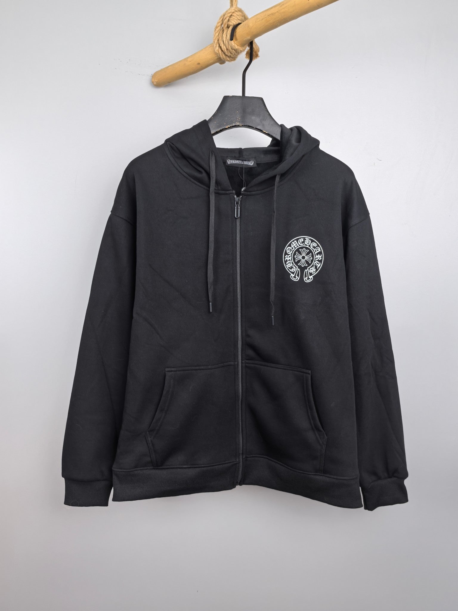 Black zip-up hoodie with hood, drawstrings, and front chest logo patch