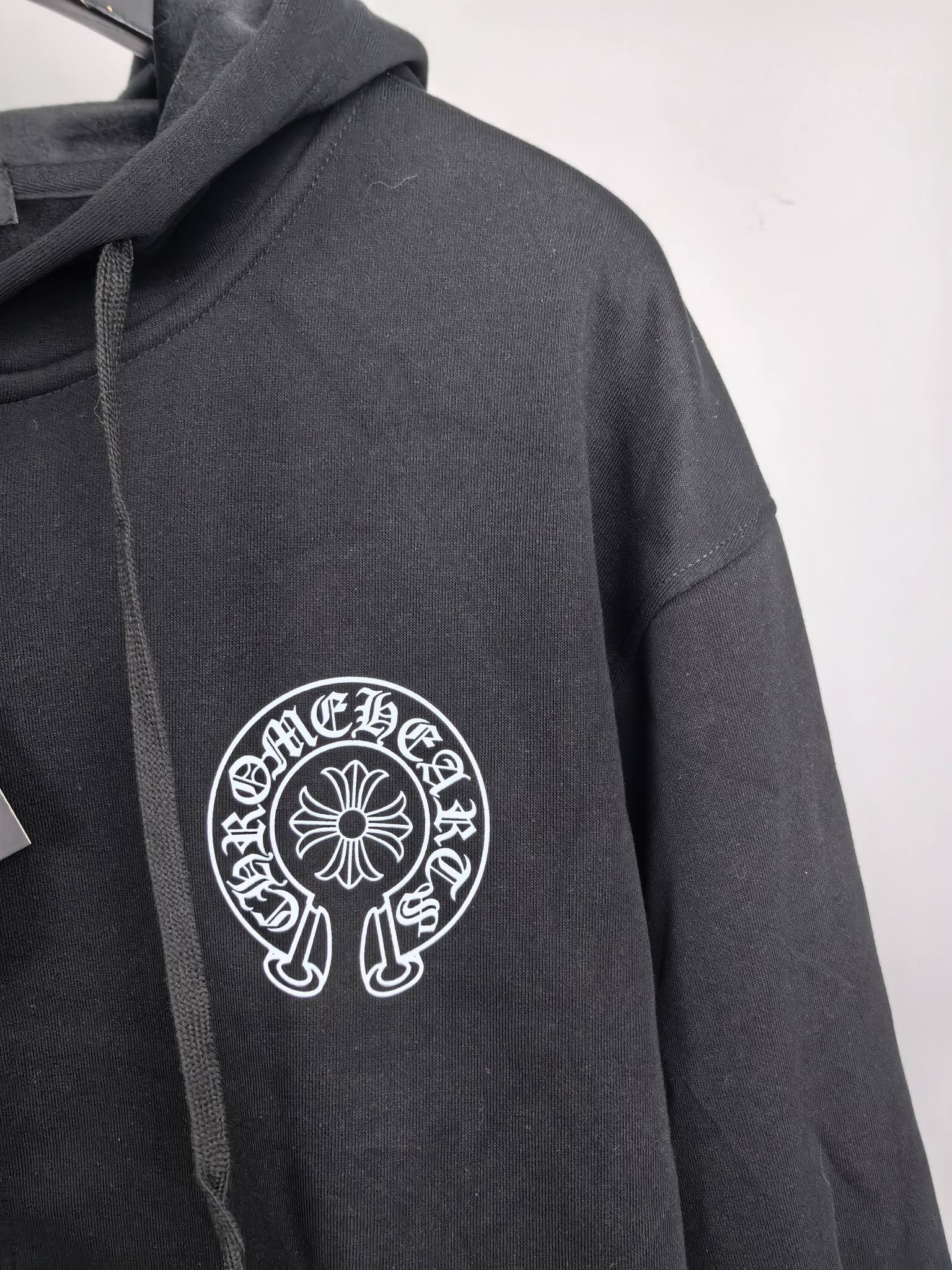 Black zip-up hoodie sleeve with circular chest logo embroidery