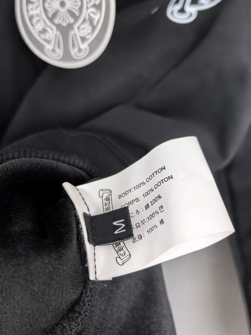 Black zip-up hoodie fabric label tag with cotton content text