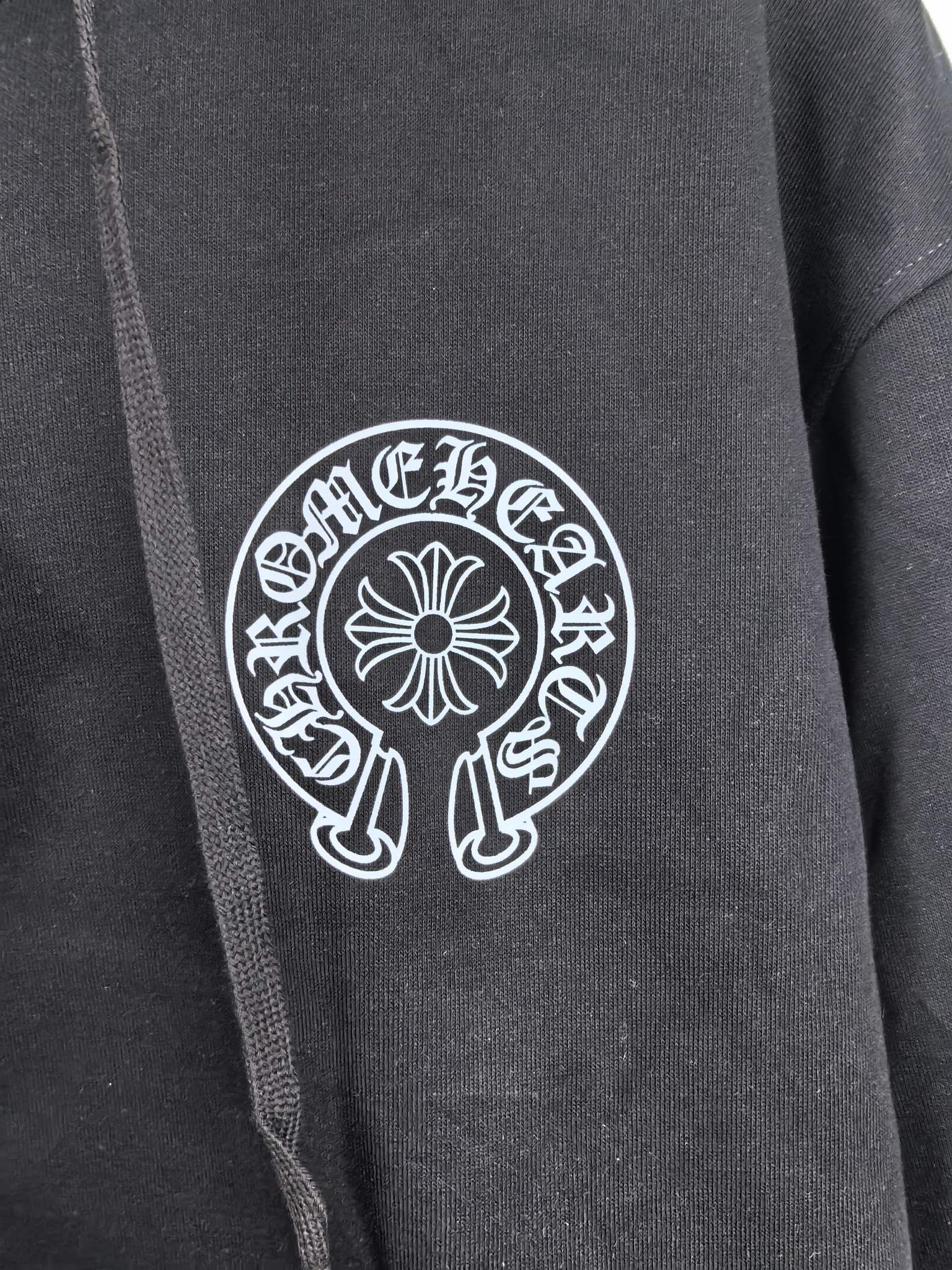 Black zip-up hoodie front with large circular logo patch