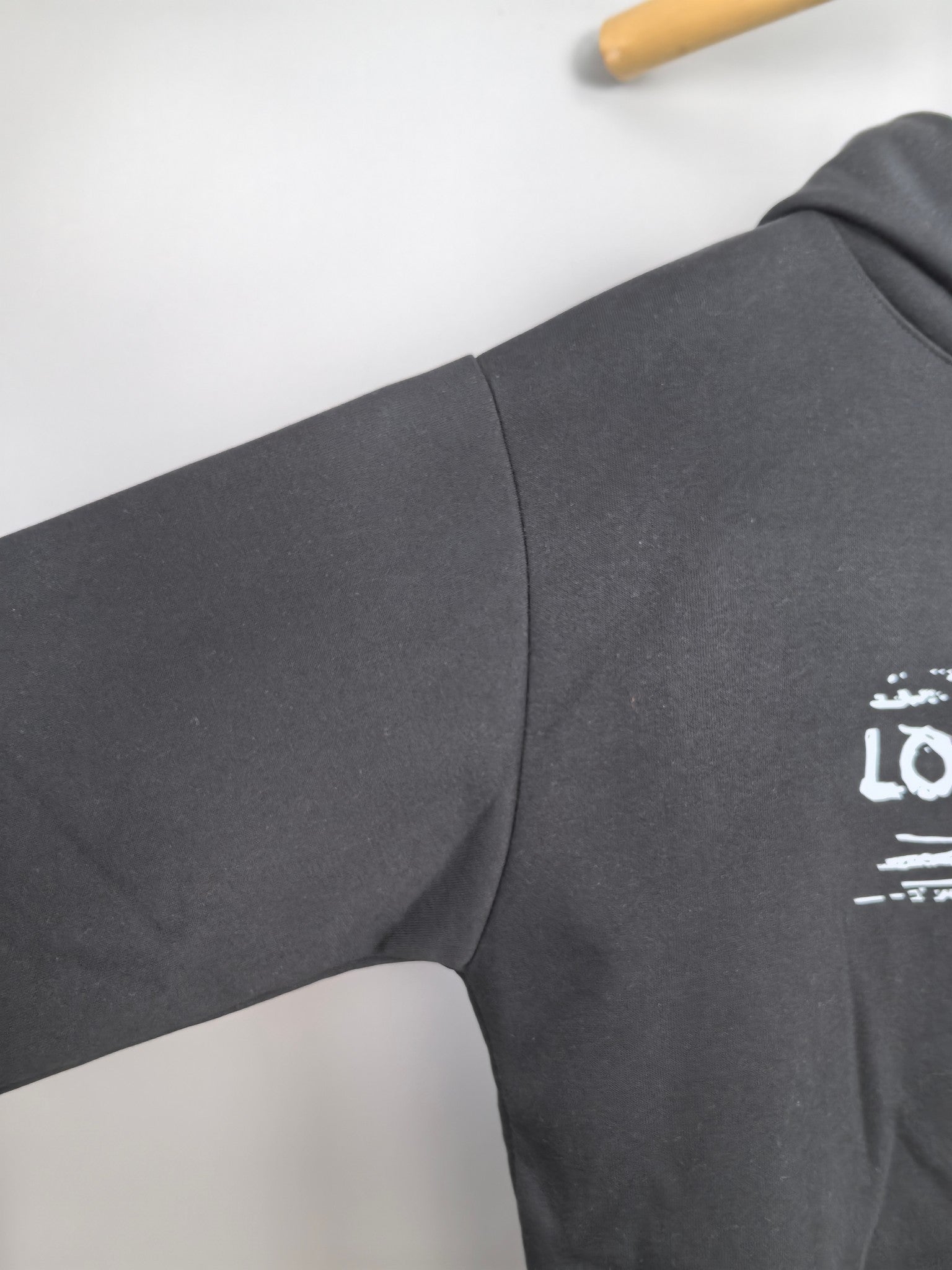 Black hoodie sleeve with small Louis Vuitton logo print near the hem.