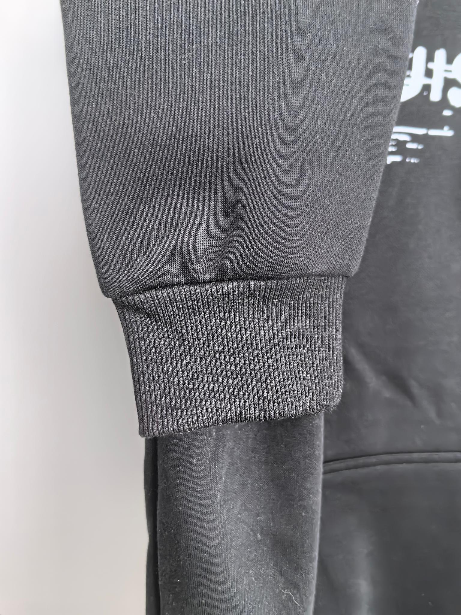 Black hoodie with ribbed knit cuffs and textured fabric near the hem.