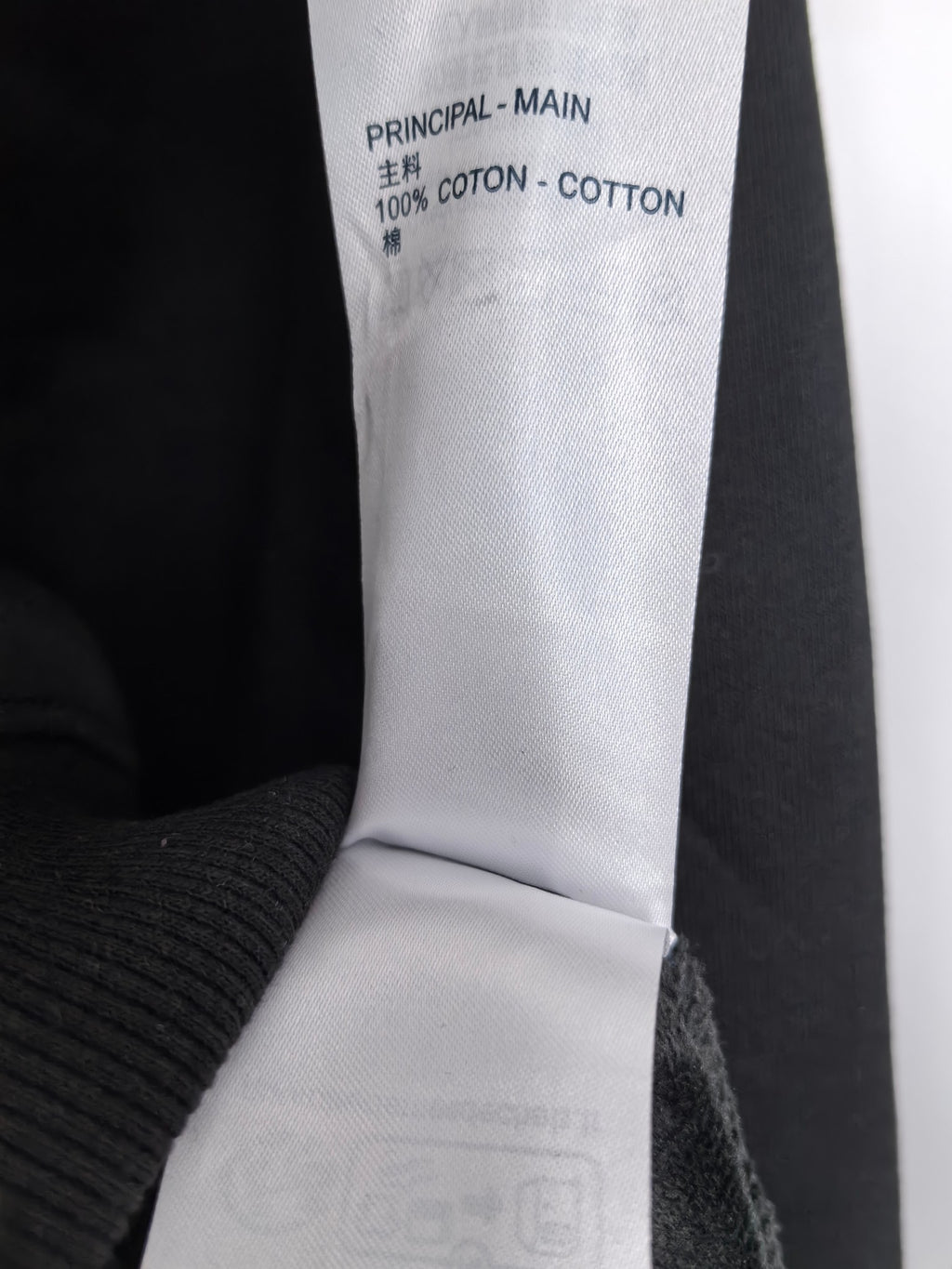 Black hoodie label reading '100% COTTON' and 'PRINCIPAL - MAIN'.