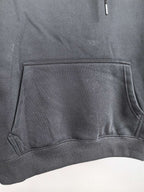 Black hoodie front pouch pocket with stitched edges and ribbed hem.