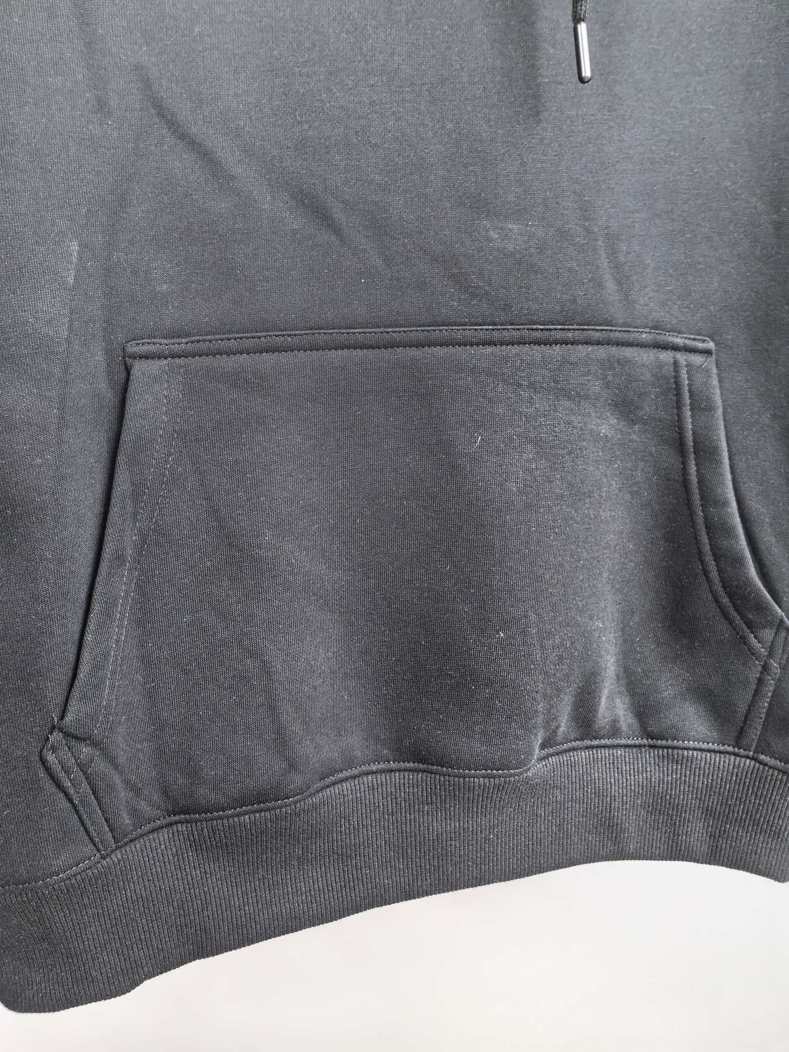 Black hoodie front pouch pocket with stitched edges and ribbed hem.