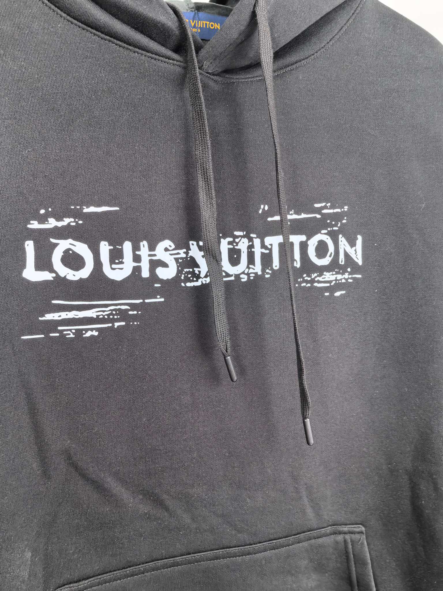 Black hoodie chest with Louis Vuitton logo print and drawstring ties.