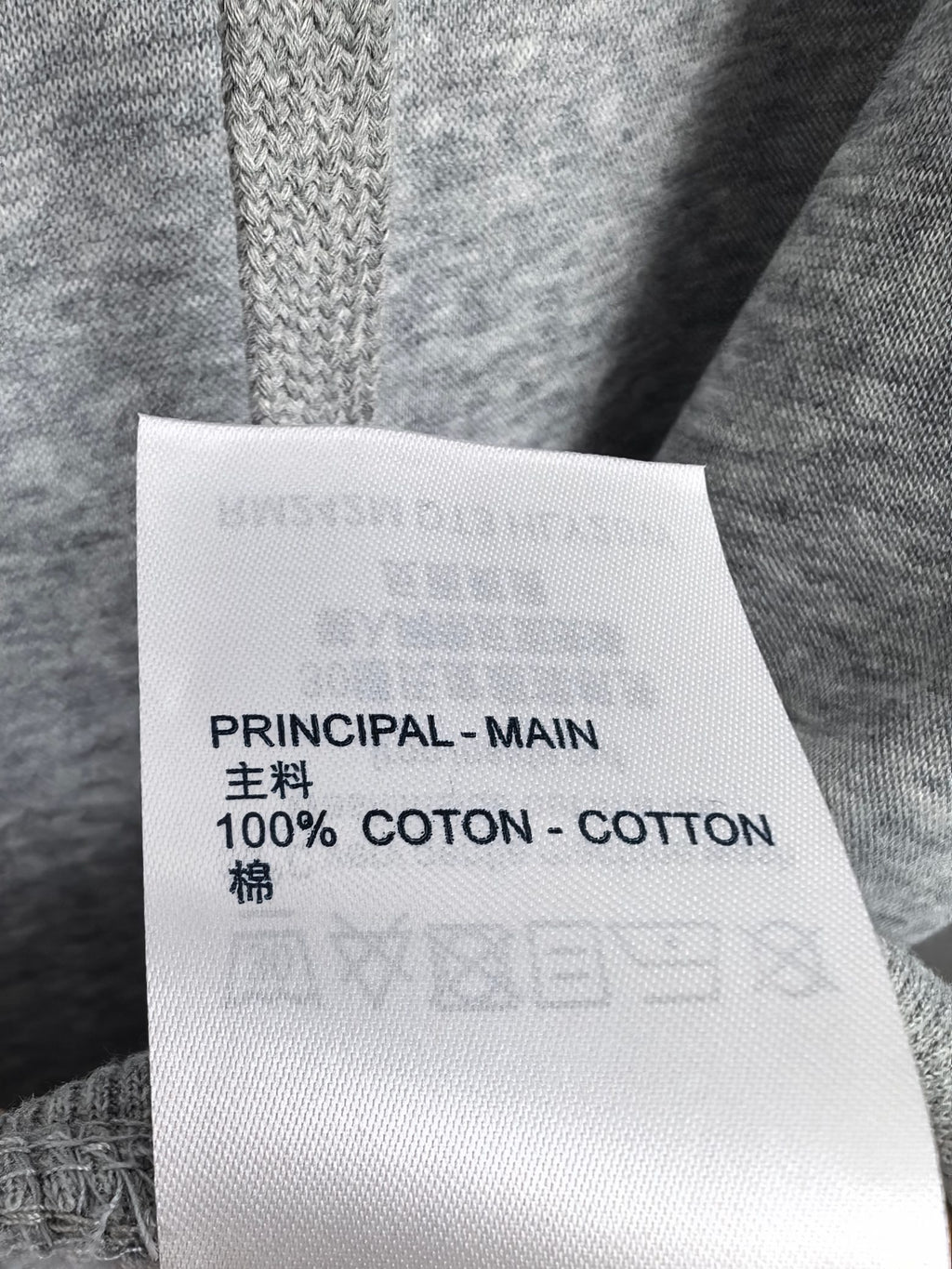 Clothing care label showing 100% cotton and Principal-Main text