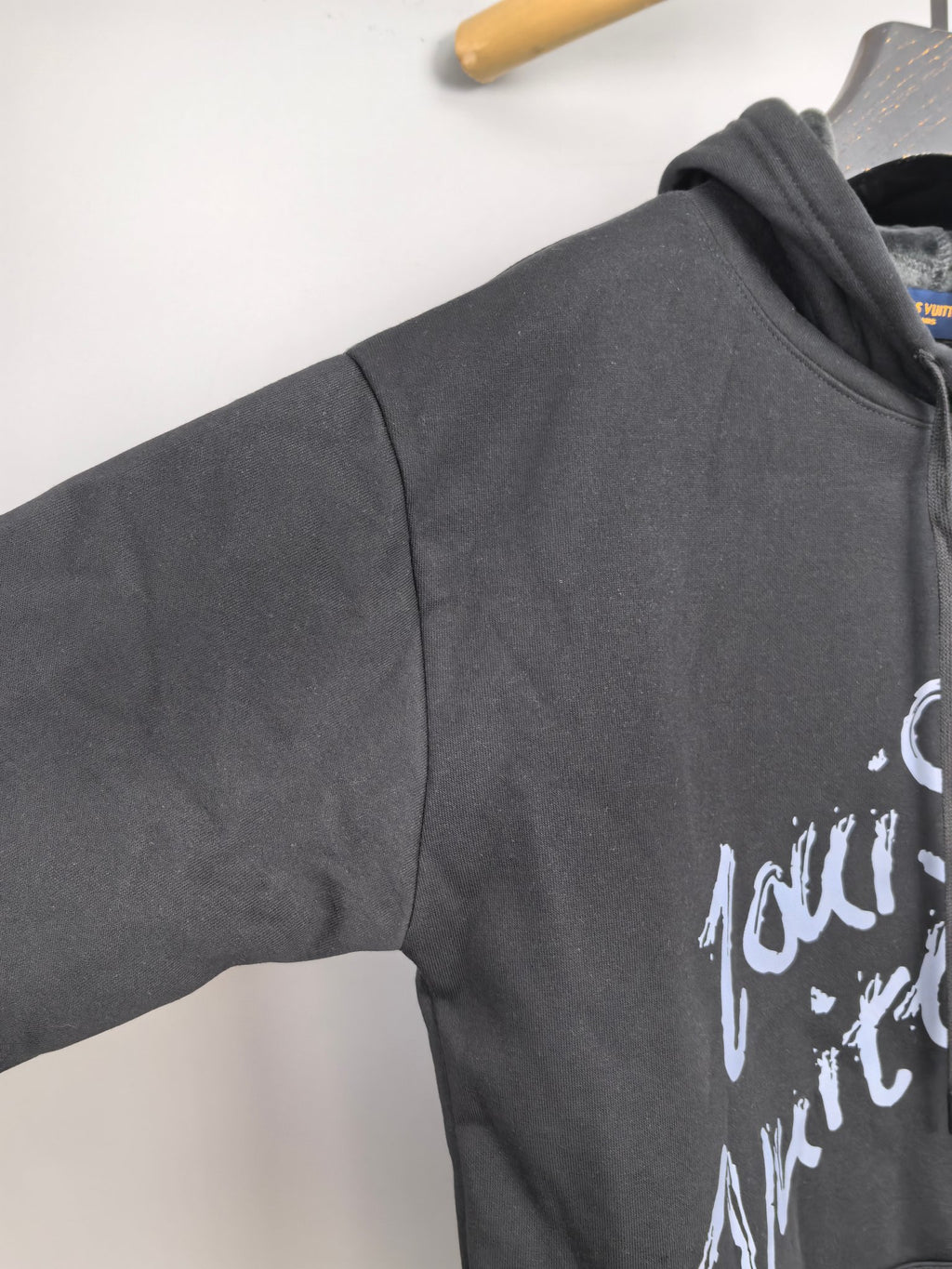 Dark gray hoodie sleeve detail with white graphic logo print
