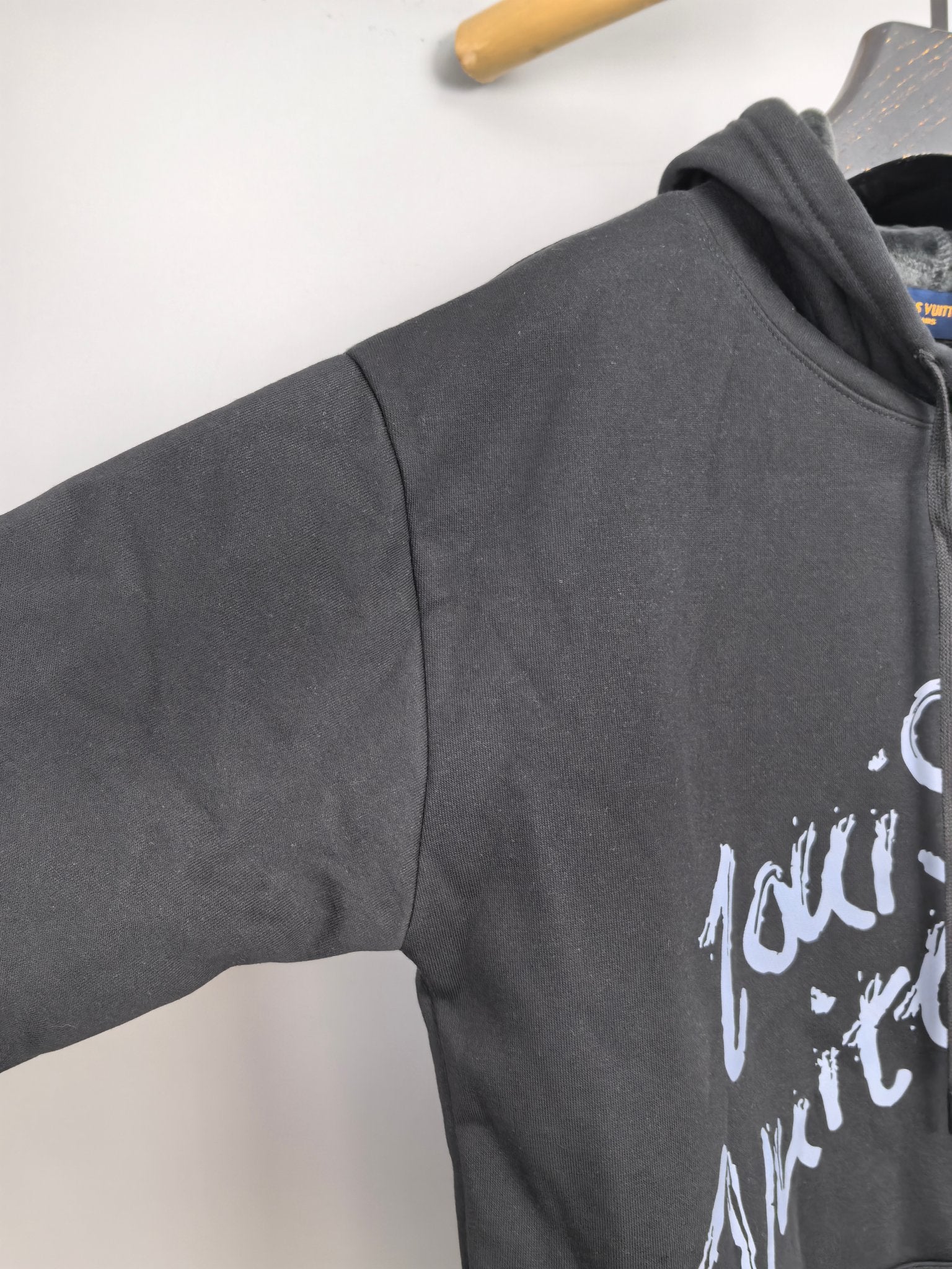 Dark gray hoodie sleeve detail with white graphic logo print