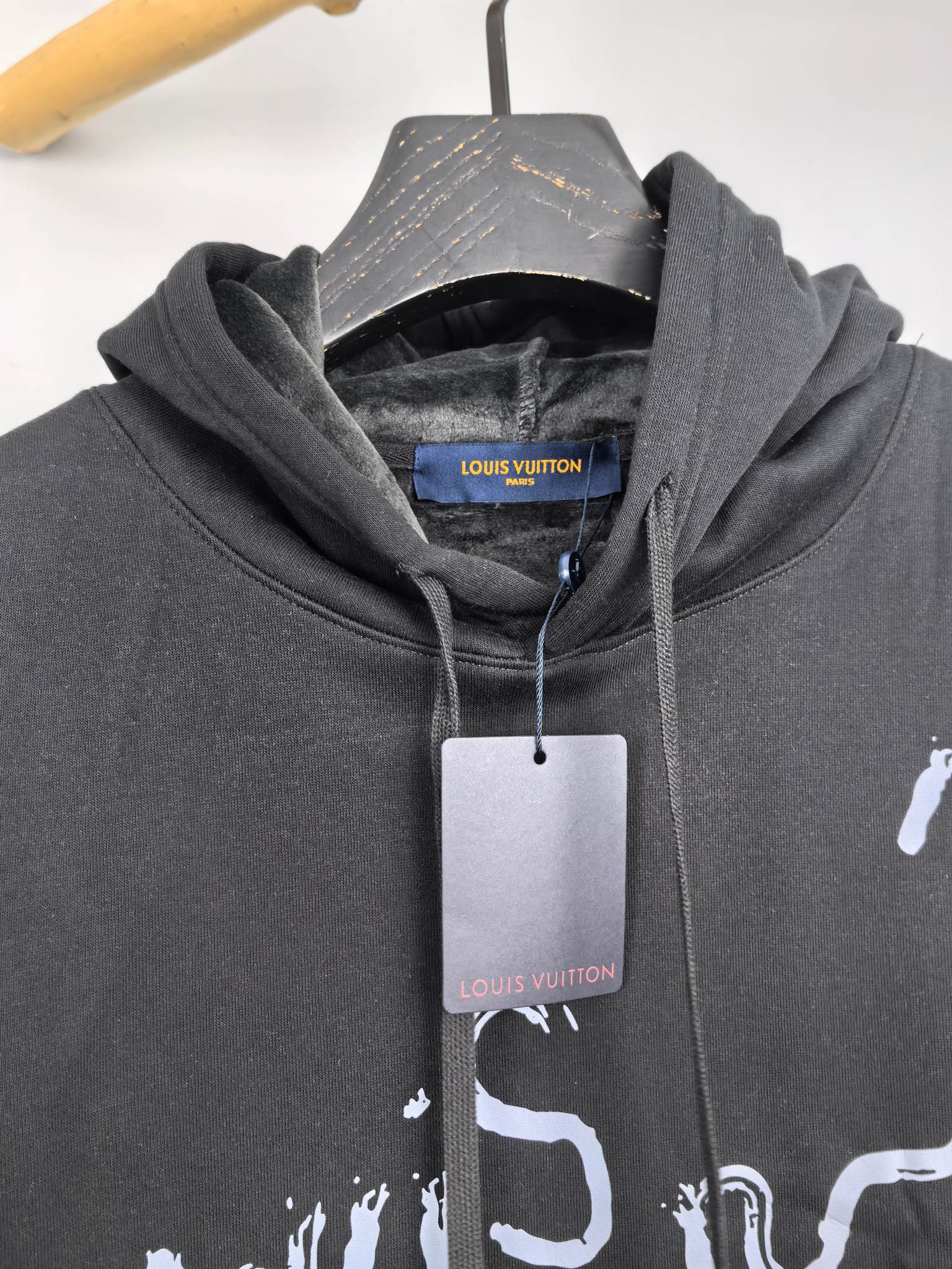 Dark gray hoodie close-up of hood, drawstrings, and white graphic logo print