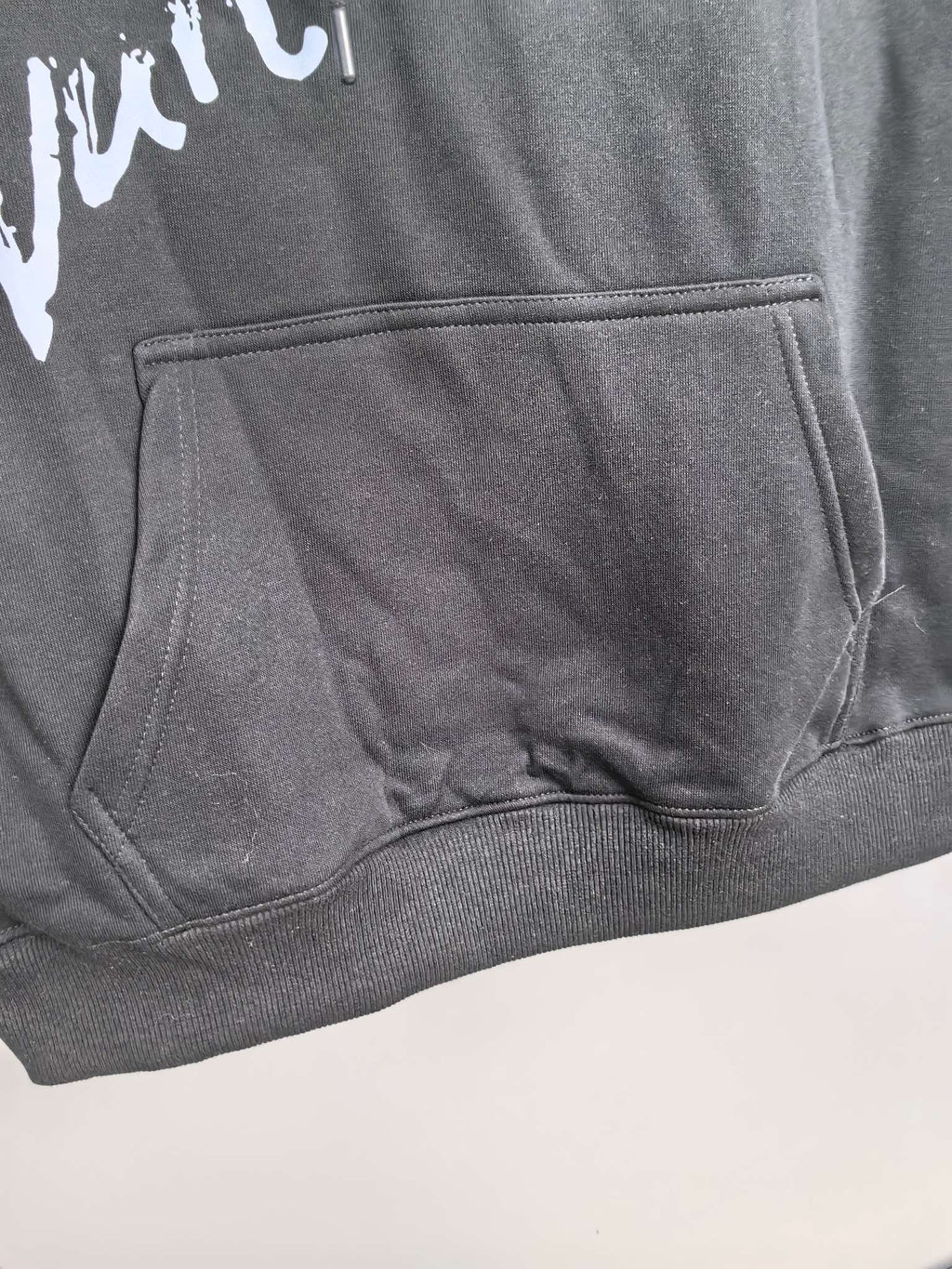 Dark gray hoodie kangaroo pocket with white graphic logo detail
