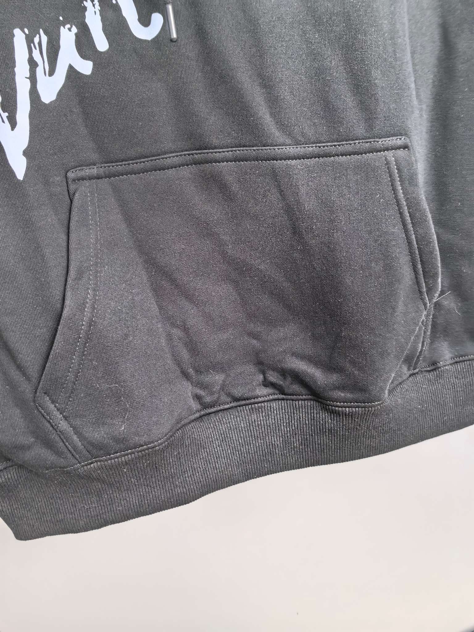 Dark gray hoodie kangaroo pocket with white graphic logo detail