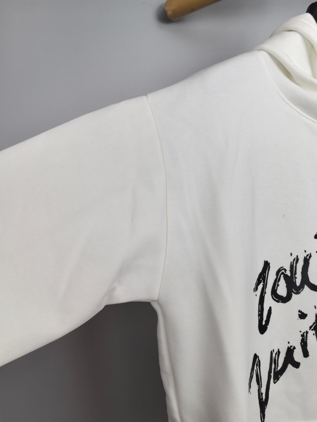 White hoodie sleeve with partial black graffiti graphic print
