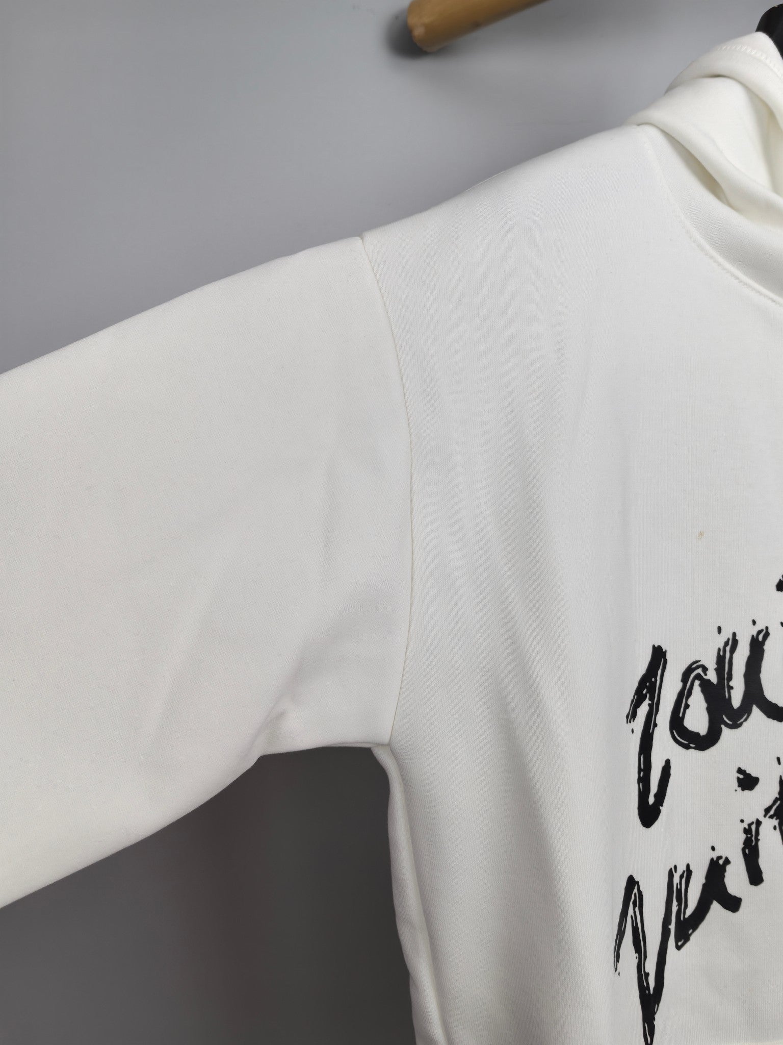 White hoodie sleeve with partial black graffiti graphic print