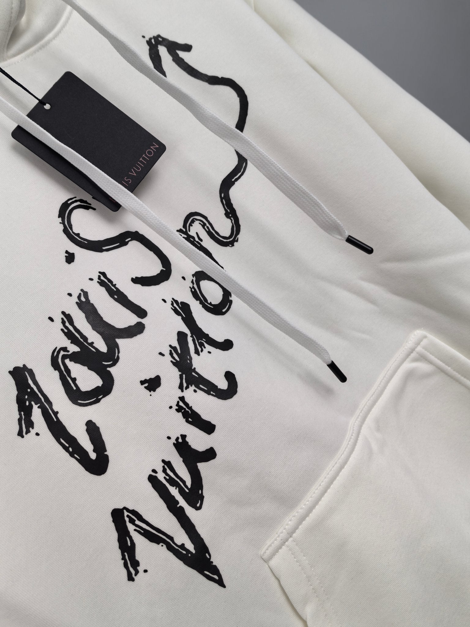 White hoodie front close-up with large black graffiti lettering and kangaroo pocket