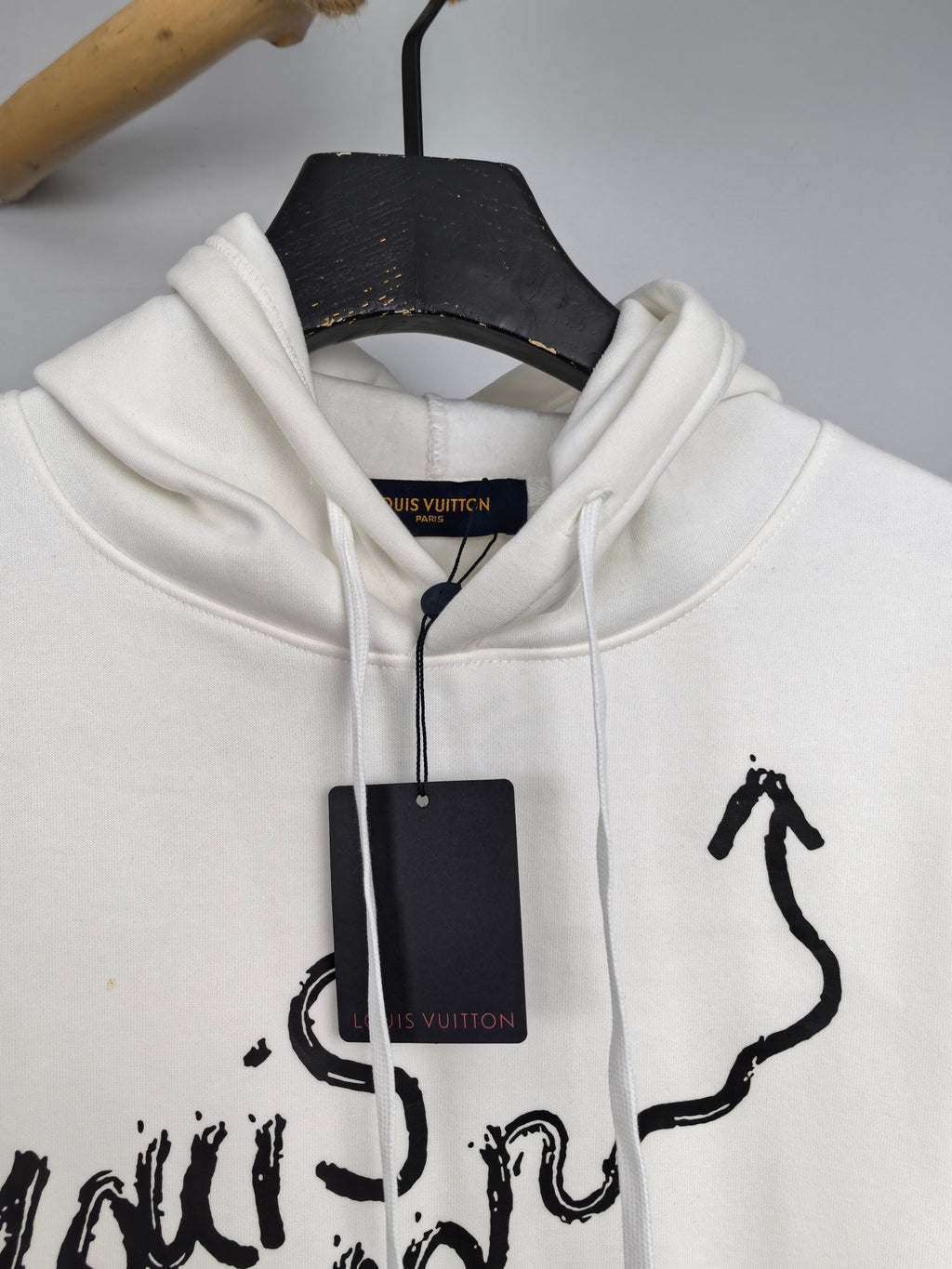 White hoodie close-up of hood, black graffiti-style graphic and hang tag