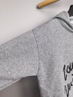 Gray hoodie sleeve and shoulder with black script graphic detail