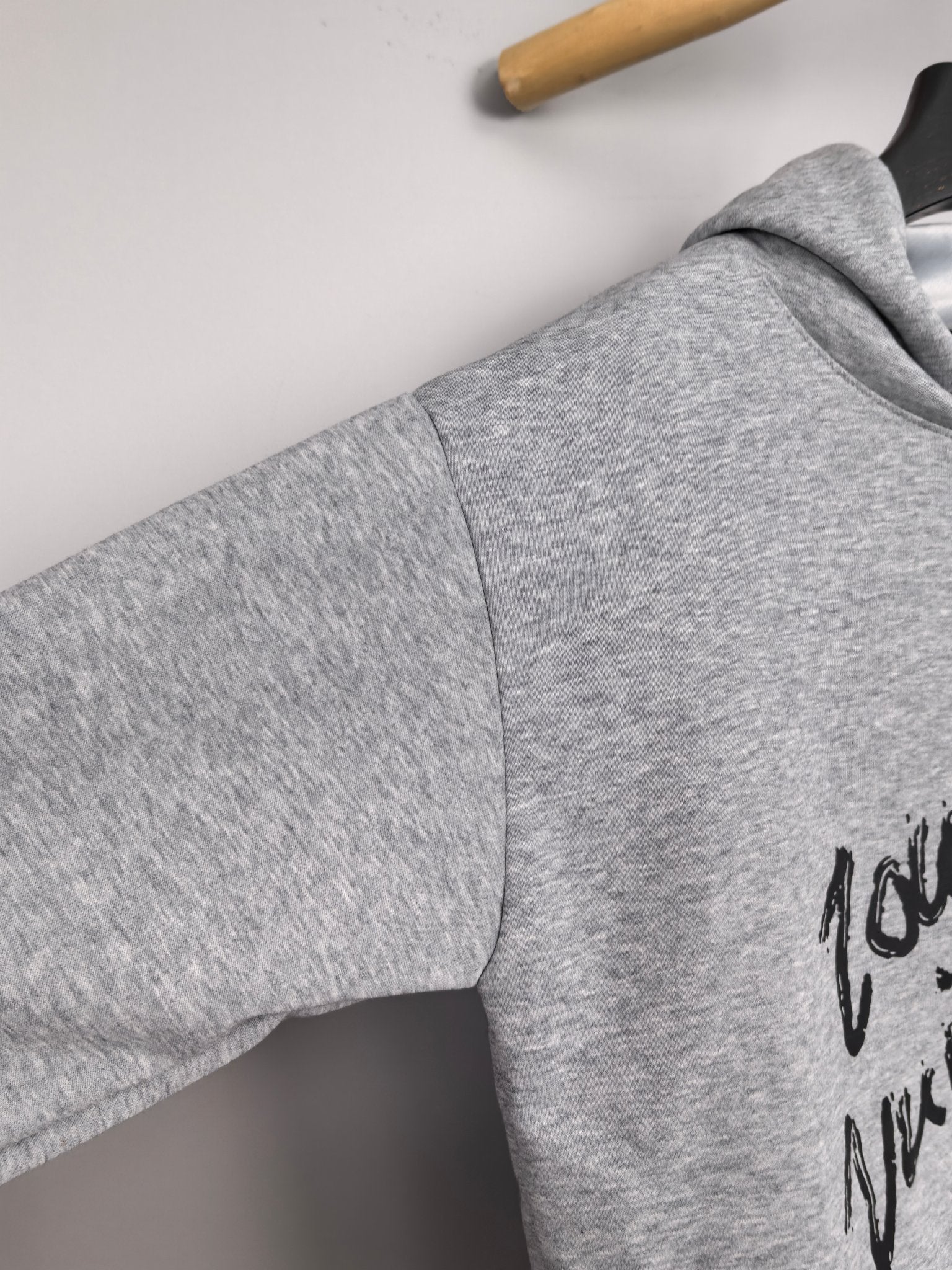 Gray hoodie sleeve and shoulder with black script graphic detail