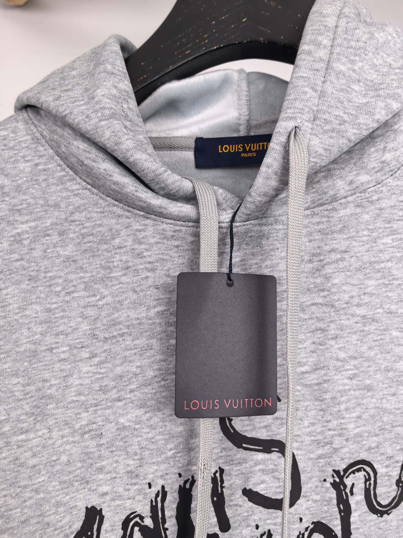 Gray pullover hoodie neckline with black script print and inner brand label