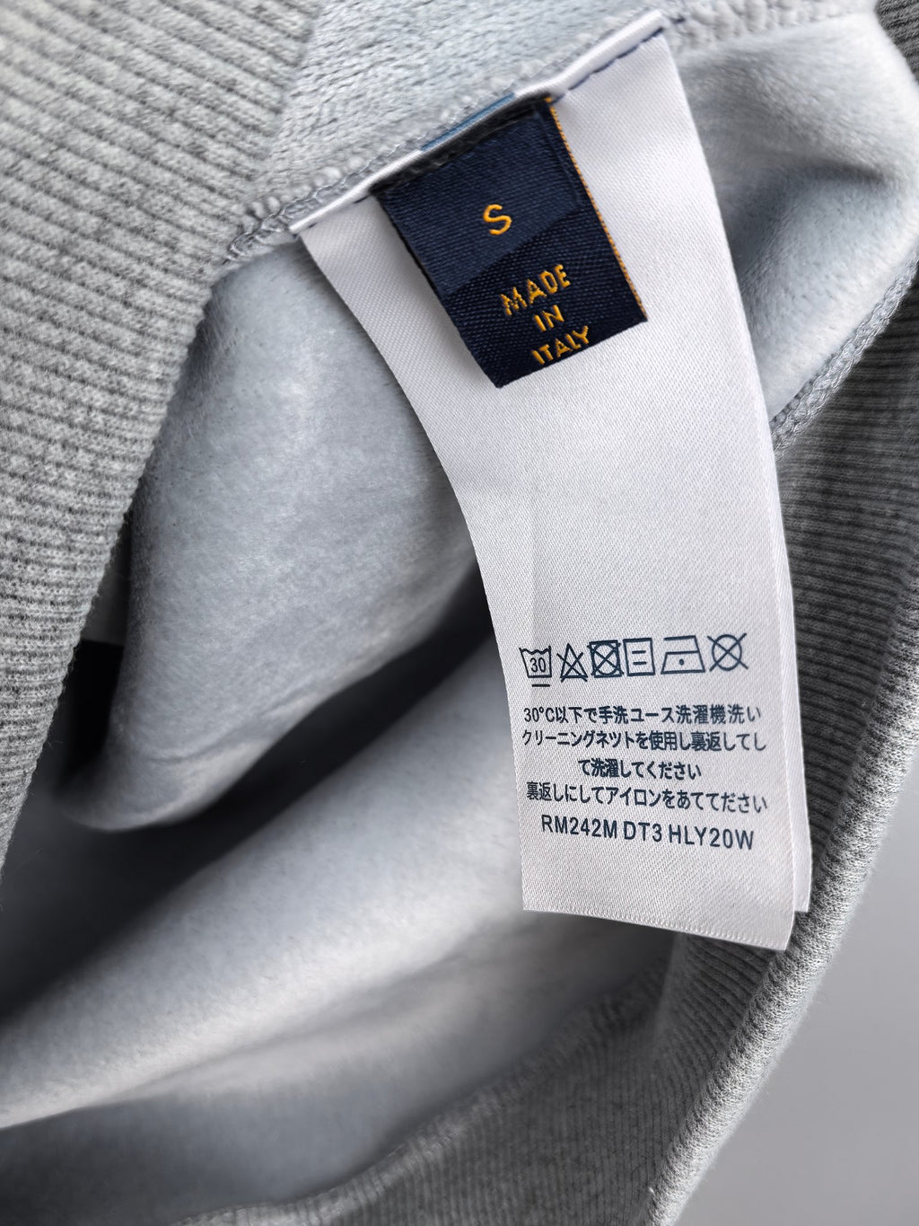 Gray hoodie fabric tag showing 'Made in Italy' and care symbols