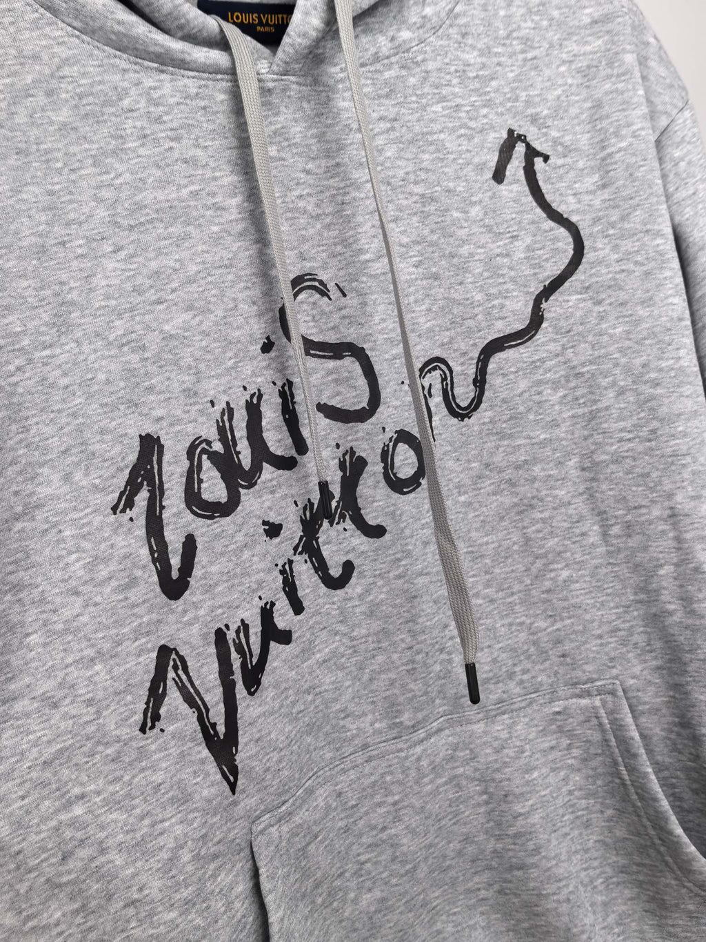 Gray pullover hoodie close-up of black script graphic on chest