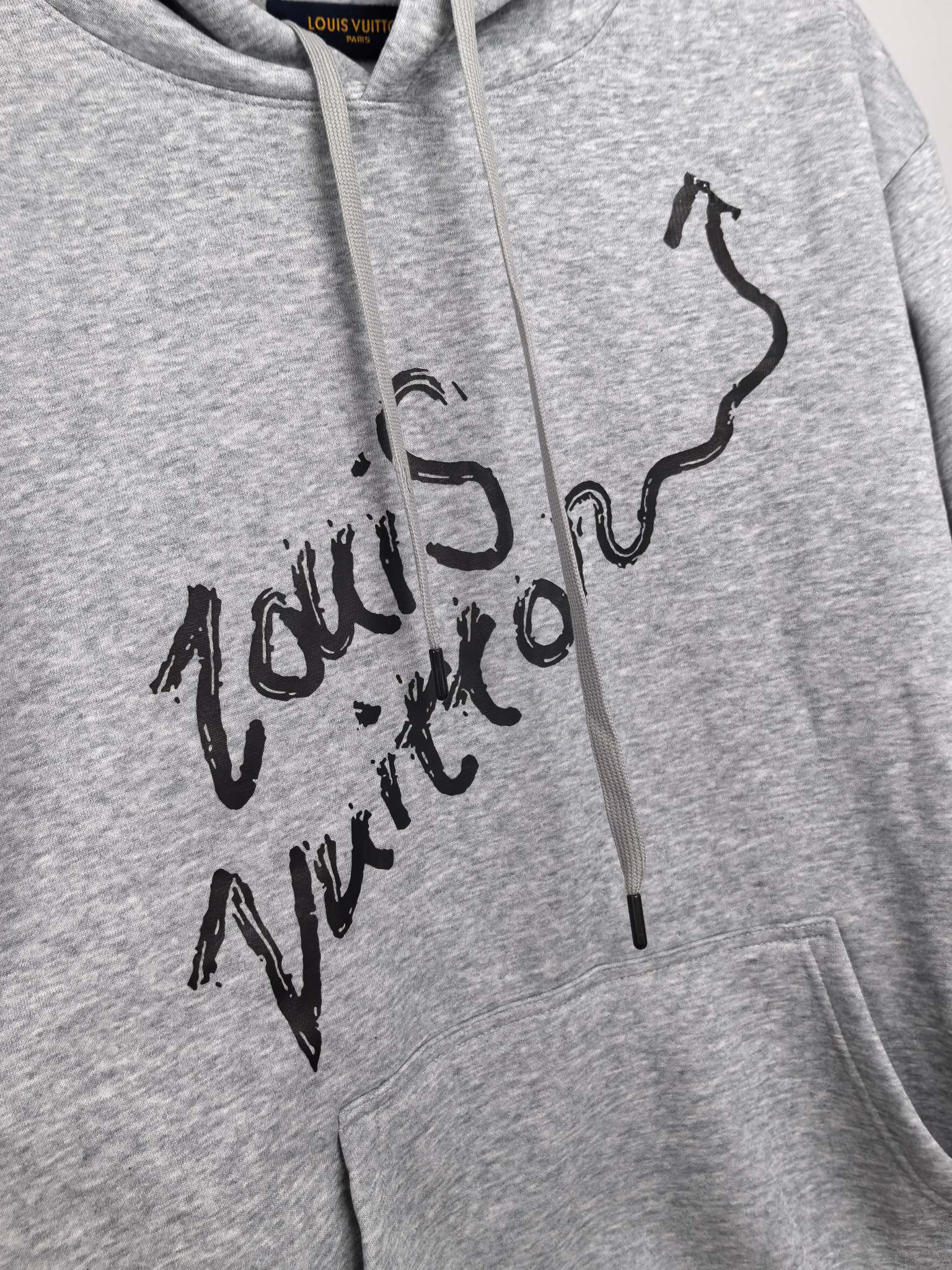 Gray pullover hoodie close-up of black script graphic on chest
