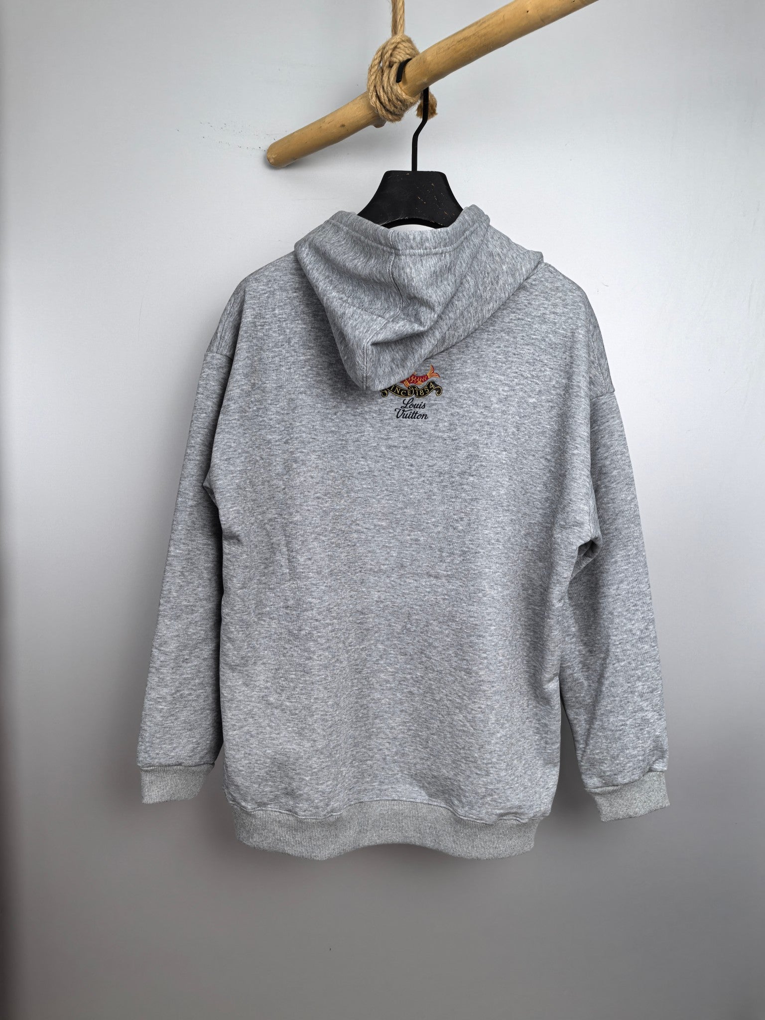 Gray long-sleeve hoodie with hood and small fish logo on the back