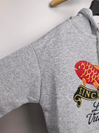 Gray hoodie sleeve with red fish and black “Since 1854” graphic patch