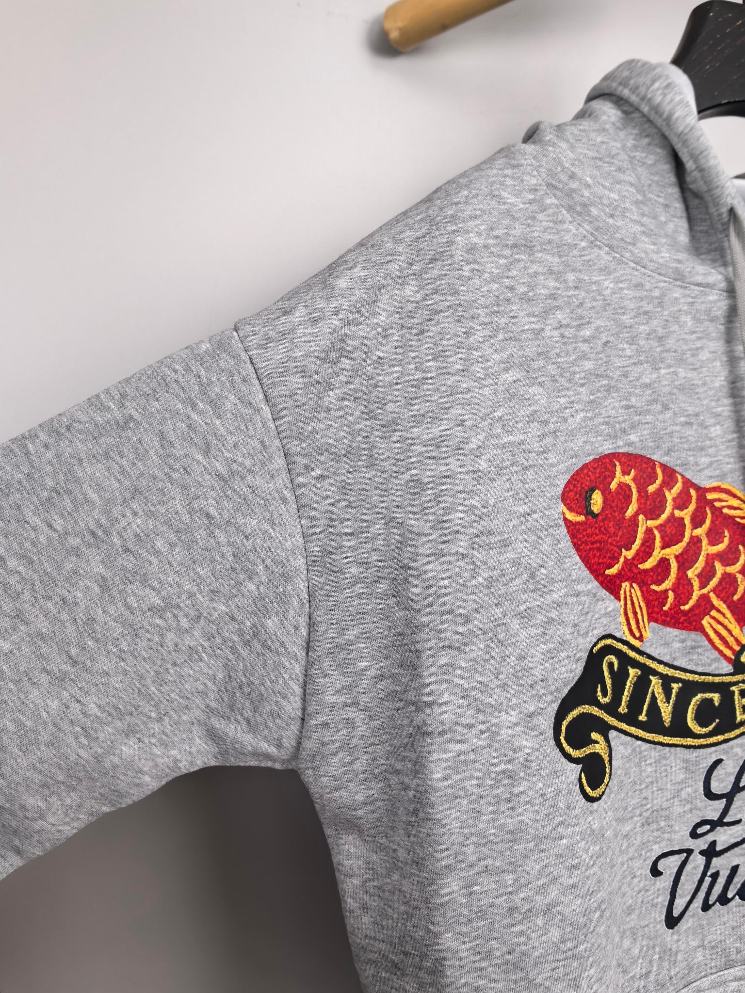 Gray hoodie sleeve with red fish and black “Since 1854” graphic patch