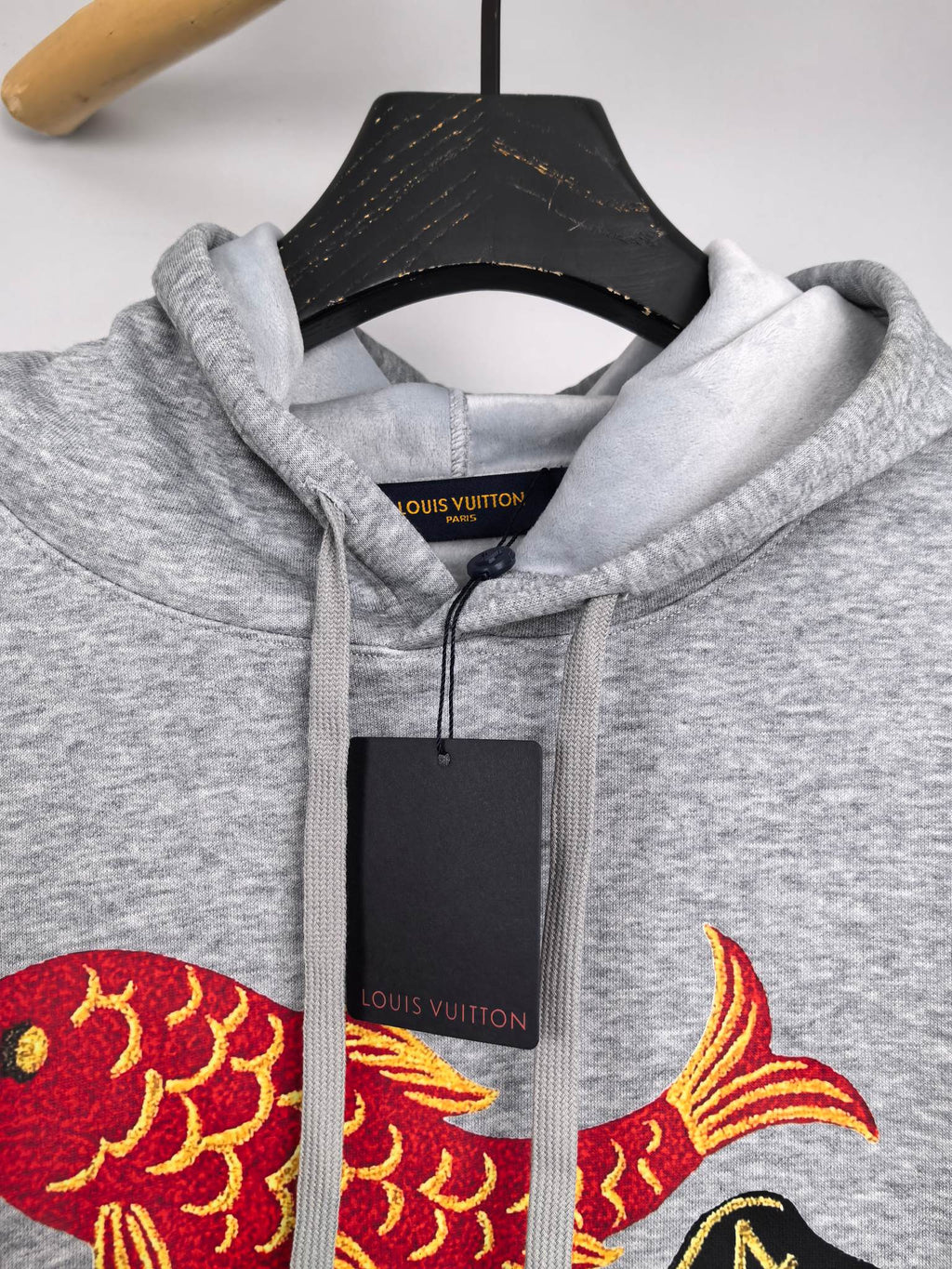 Gray hoodie close-up of hood drawstrings and Louis Vuitton fish graphic