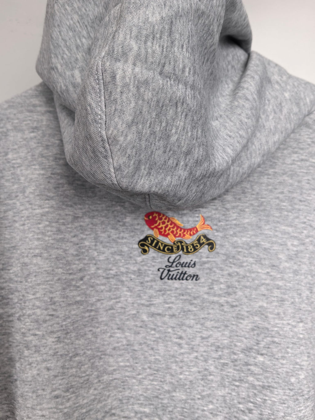 Gray hoodie back view with small fish and “Louis Vuitton” emblem