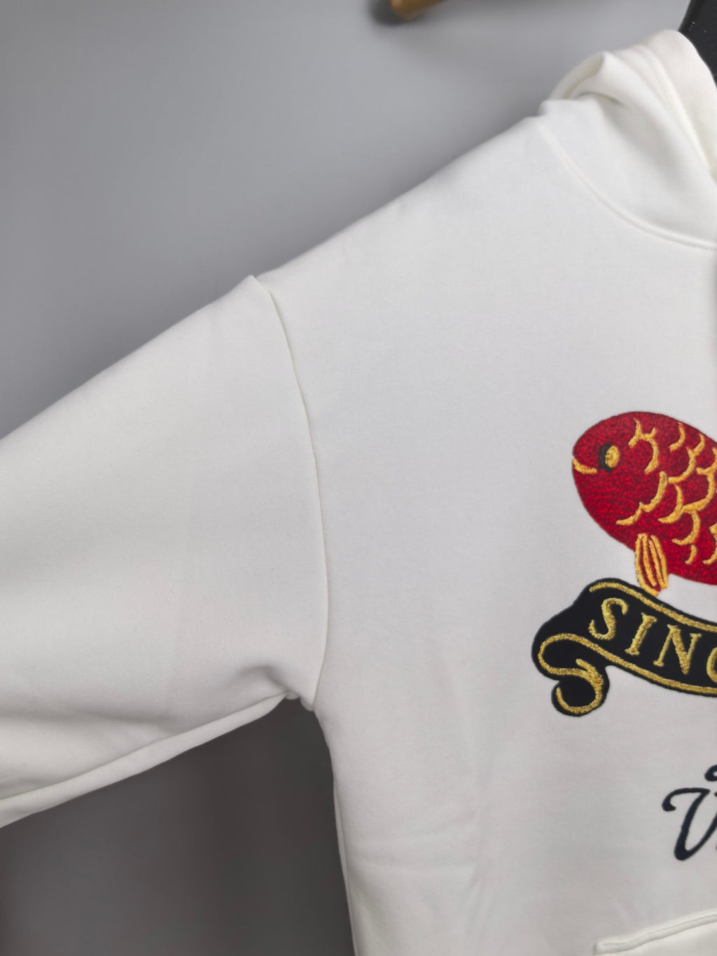 White hoodie shoulder with partial colorful fish and Louis Vuitton logo print