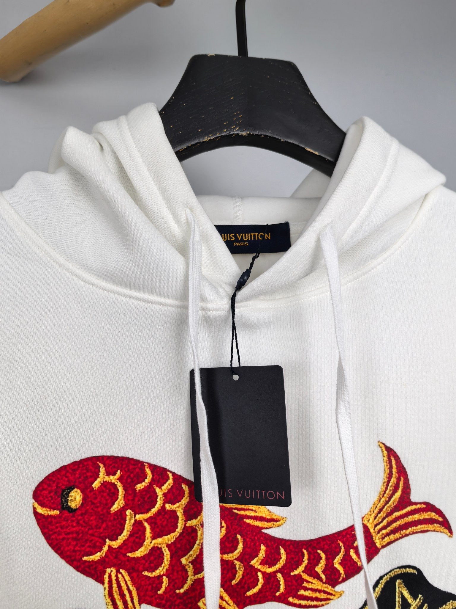White hoodie hood area with red and yellow fish graphic and Louis Vuitton branding