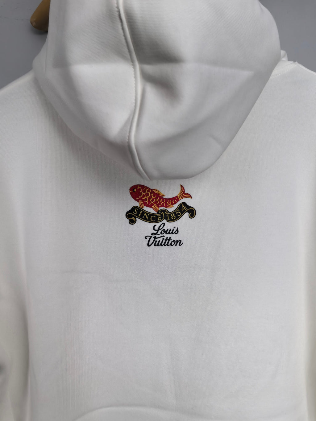 White hoodie with hood and small fish emblem with Louis Vuitton text