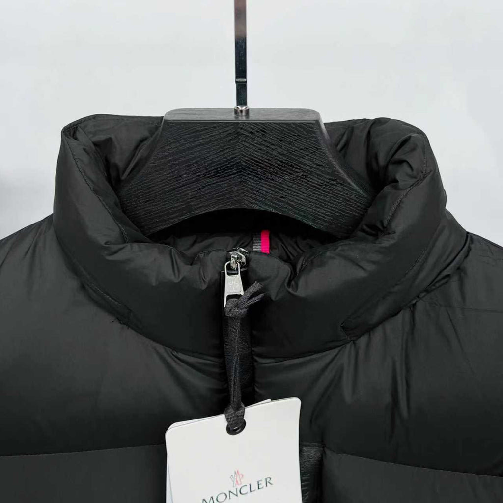 Black puffer jacket collar with half-zip front and Moncler logo hang tag