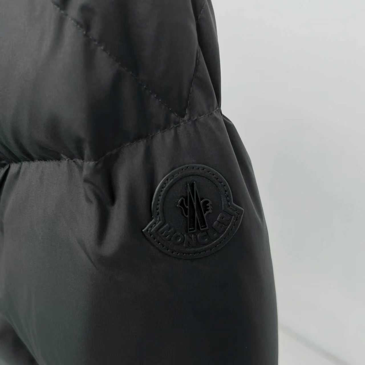 Black puffer jacket sleeve with embossed Moncler patch