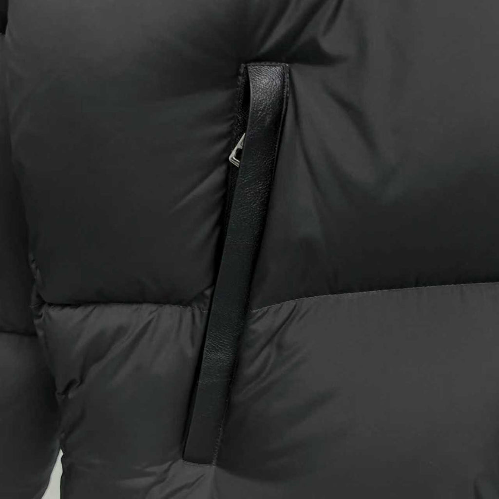 Black puffer jacket detail, front zipper placket and quilted stitching
