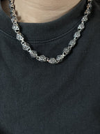 Star-motif square-link chain necklace detail on neckline, silver-tone with dark accents