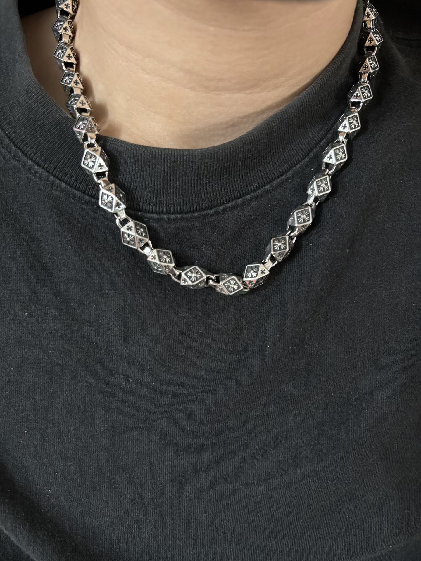 Star-motif square-link chain necklace worn at collar, silver-tone with dark accents