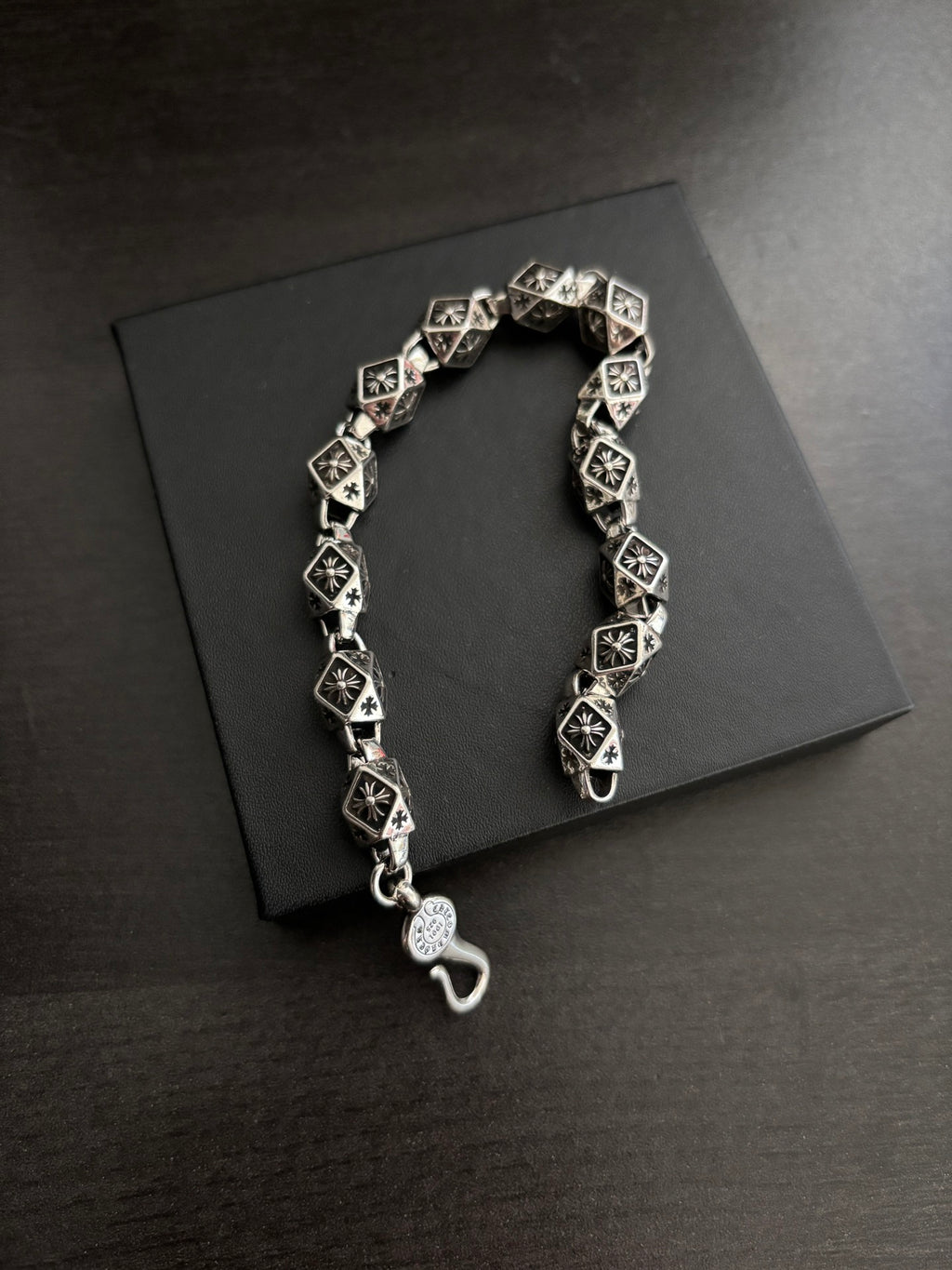 Chrome bracelet with black square links, round clasp charm, and hook closure.