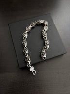 Chrome bracelet with black square links, round clasp charm, and hook closure.